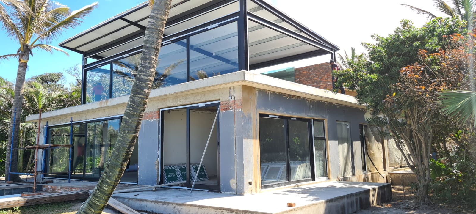 Coastal dining area with large aluminium glass doors showcasing scenic views and modern architectural style.