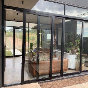 Modern aluminium sliding door design connecting indoor living area to outdoor space with glass and black frames.
