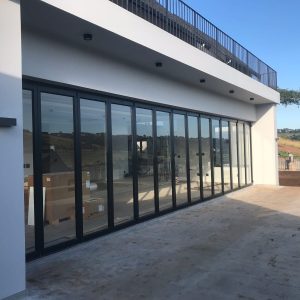 Aluminium folding stacking doors fully opened to create seamless indoor-outdoor flow in a modern residential space.