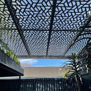 Laser-cut aluminium pergola in a geometric design, a functional and stylish use of perforated cladding panels.