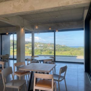 Coastal dining area with large aluminium glass doors showcasing scenic views and modern architectural style.